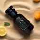 erba pure dupe inspired bottle on a sandy surface with lemons and an orange.