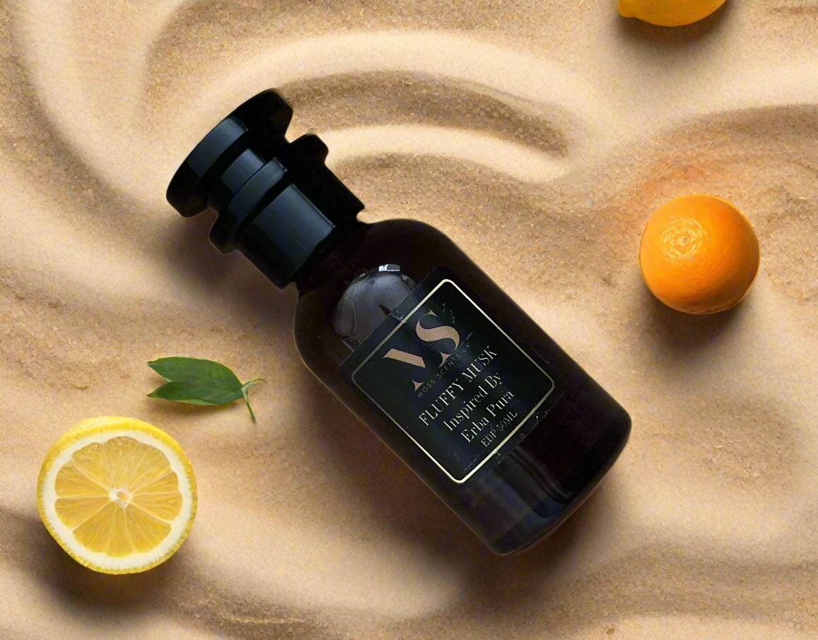 erba pure dupe inspired bottle on a sandy surface with lemons and an orange.